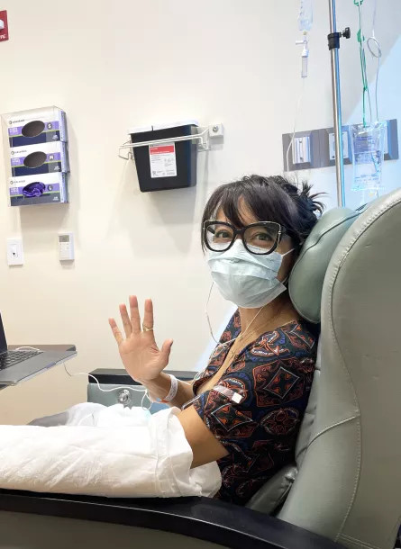 Woman waving in chemo chair