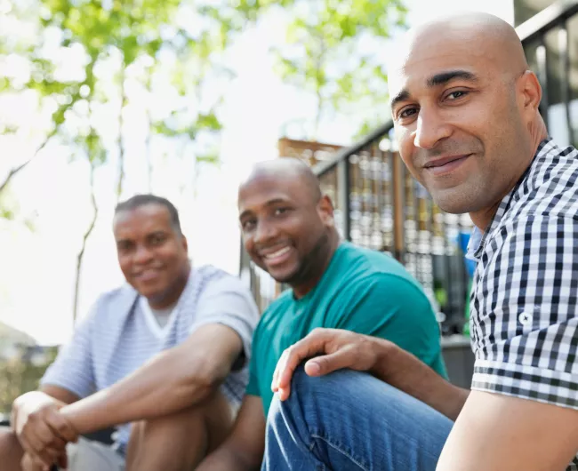 Three men outside sitting 