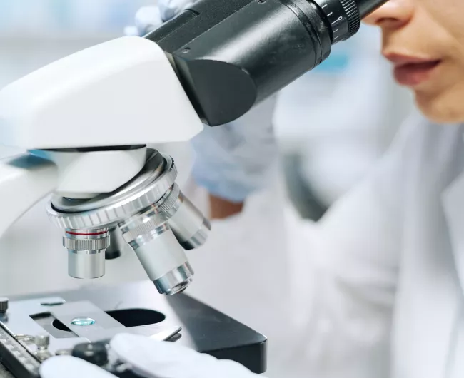 female researcher using microscope