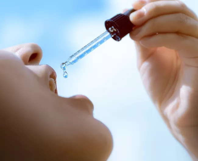 young person takes medicine from a dropper