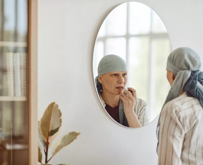 woman in light blue scarf looking in the mirror