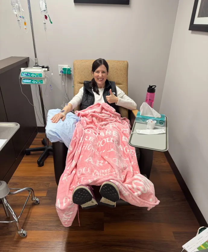Woman giving a thumbs up in chemo chair